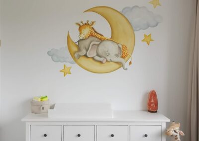 Een muurschildering van een maan met een slapende olifant en giraffe.